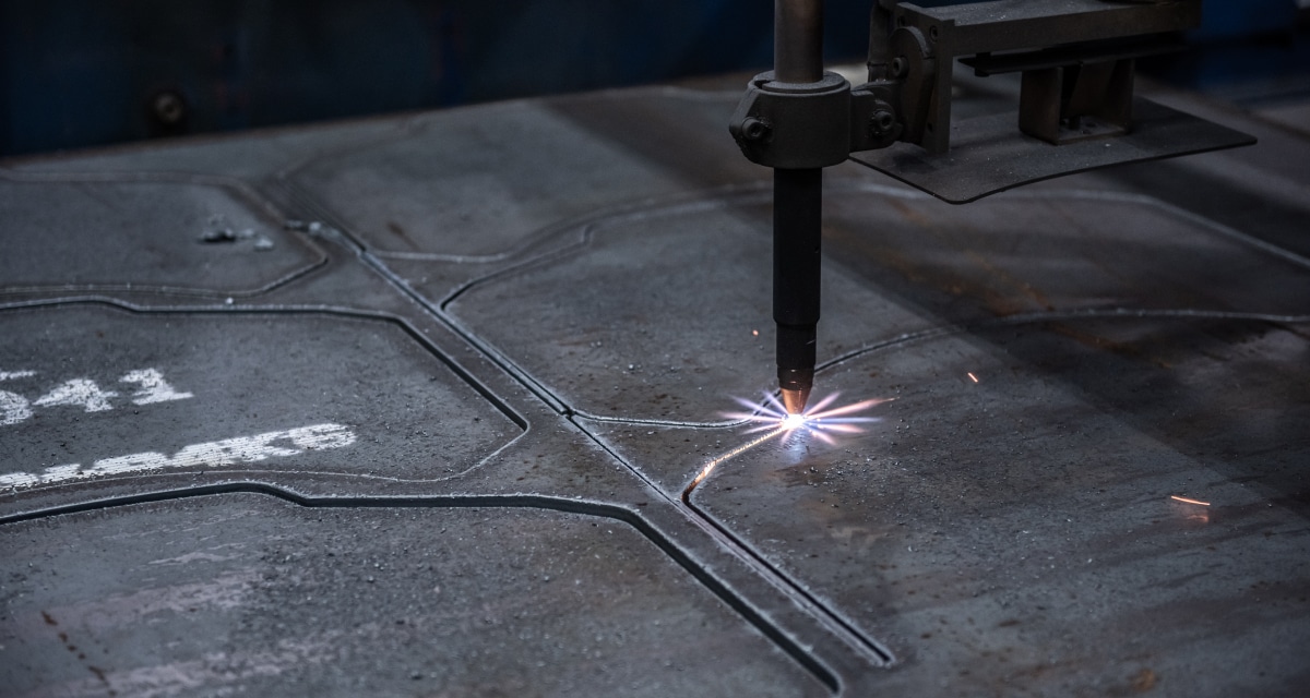 En maskin som skär genom en metallplåt med gnistor som flyger i en tillverkningsmiljö.